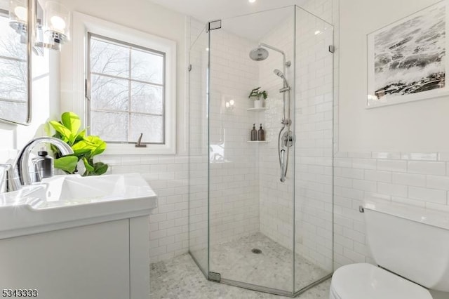 bathroom featuring toilet, a stall shower, tile walls, and vanity