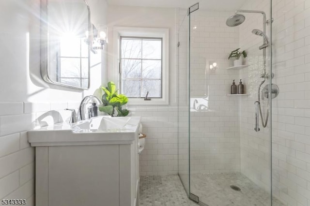 full bathroom featuring vanity, a shower stall, and tile walls