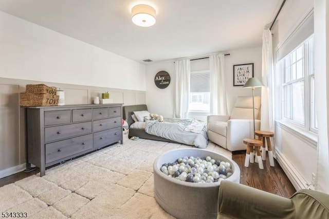 bedroom with a wainscoted wall and wood finished floors