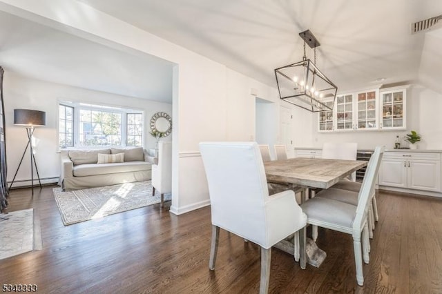 dining space featuring visible vents, a notable chandelier, dark wood finished floors, baseboards, and baseboard heating