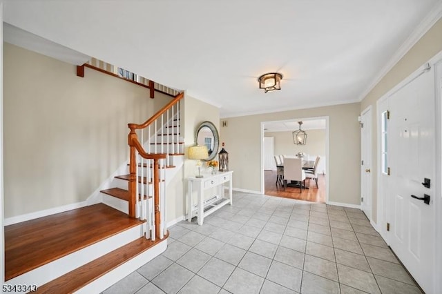 foyer entrance with light tile patterned flooring, stairway, crown molding, and baseboards