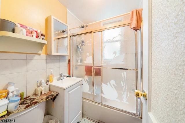 full bath featuring bath / shower combo with glass door, a sink, tile walls, toilet, and tasteful backsplash