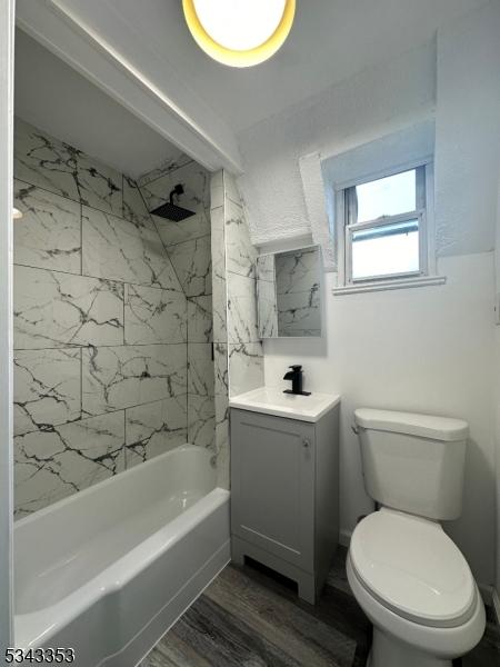 bathroom with toilet, vanity, bathing tub / shower combination, and wood finished floors