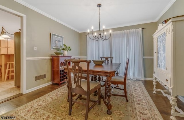 dining space with visible vents, wood finished floors, and ornamental molding