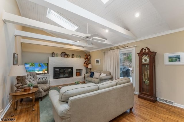 living area with light wood finished floors, visible vents, a brick fireplace, baseboards, and lofted ceiling with skylight