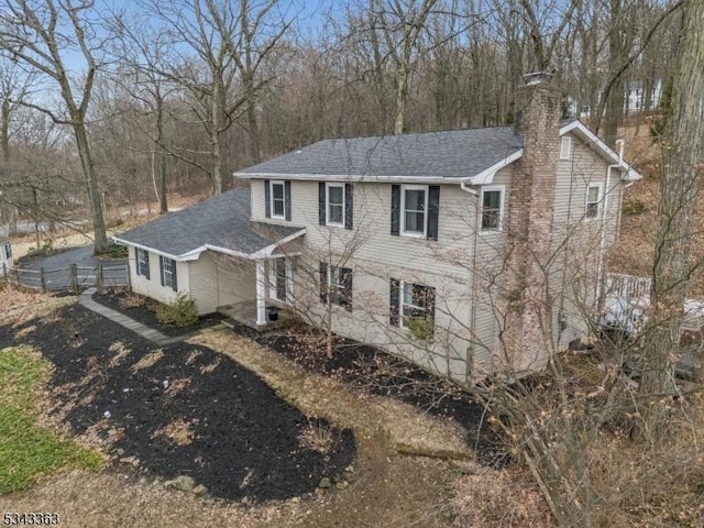 view of front of home featuring fence, roof with shingles, and a chimney