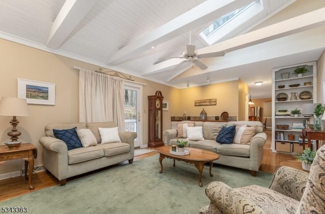 living area with wood finished floors, baseboards, vaulted ceiling with skylight, ornamental molding, and ceiling fan