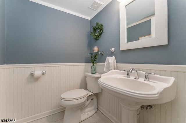 half bath featuring visible vents, a wainscoted wall, lofted ceiling, tile patterned floors, and toilet