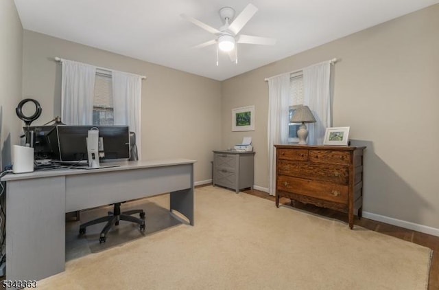 office featuring light carpet, a ceiling fan, and baseboards