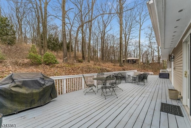 wooden terrace featuring outdoor dining area and a grill