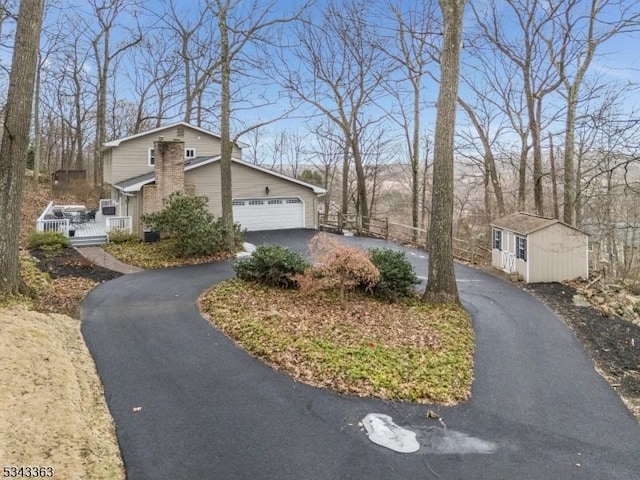 view of side of home with aphalt driveway, an outbuilding, an attached garage, and fence