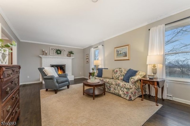 living room with ornamental molding, a fireplace, baseboards, and wood finished floors