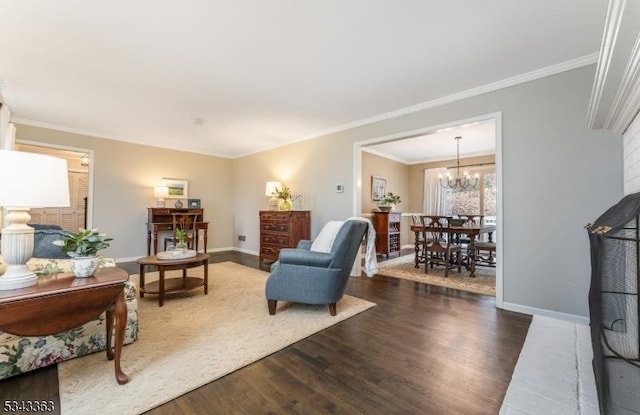 living area featuring crown molding, a notable chandelier, wood finished floors, and baseboards