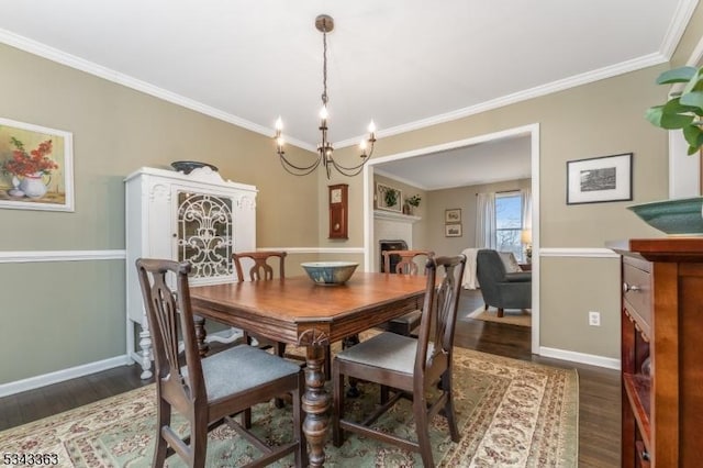 dining area with ornamental molding, a fireplace, baseboards, and dark wood-style flooring