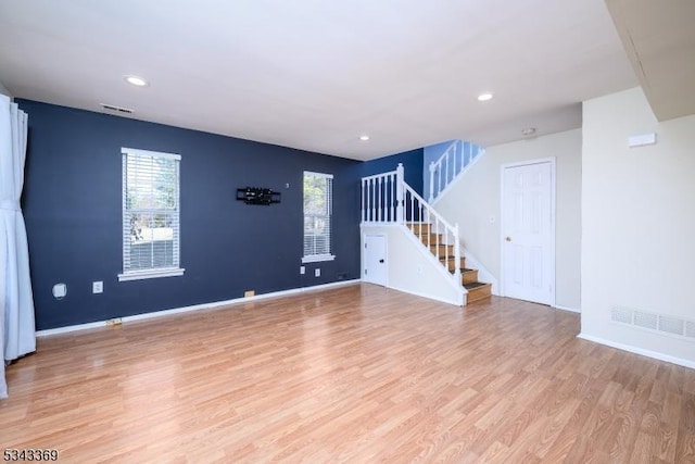 unfurnished living room featuring stairs, baseboards, visible vents, and light wood finished floors