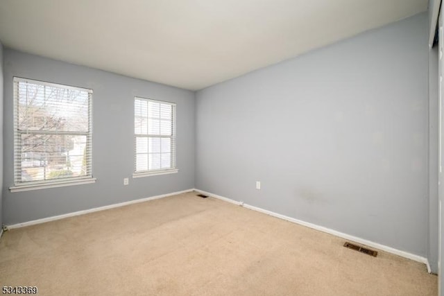 unfurnished room featuring visible vents, light colored carpet, and baseboards