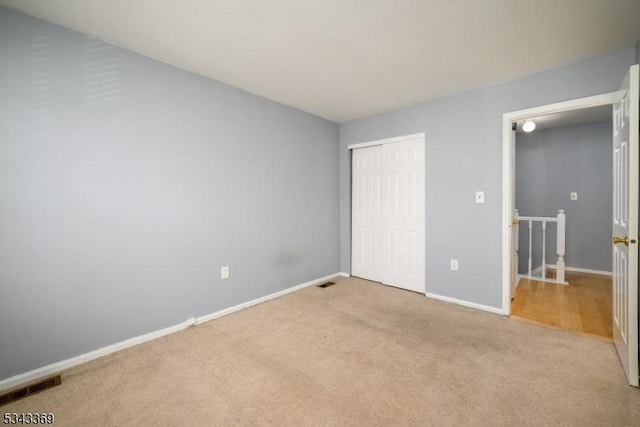 unfurnished bedroom with a closet, carpet flooring, baseboards, and visible vents