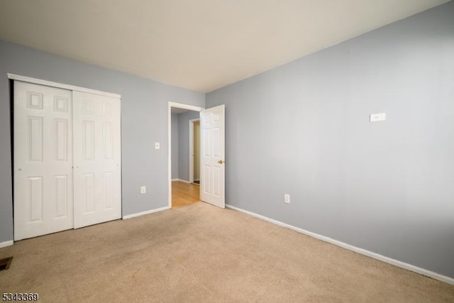 unfurnished bedroom with a closet, carpet flooring, and baseboards