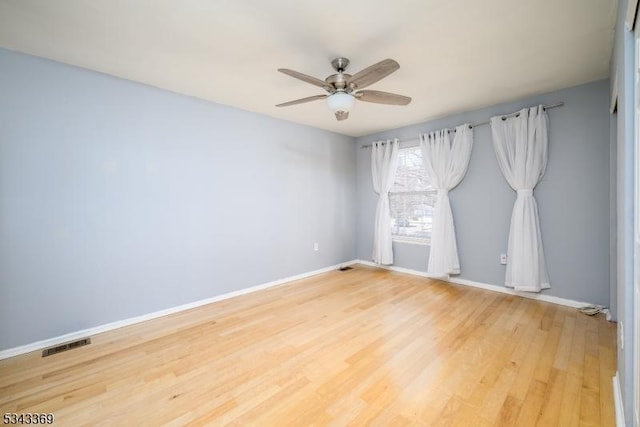 empty room with visible vents, light wood-style flooring, baseboards, and ceiling fan