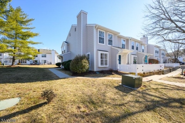 back of property with a residential view, a lawn, a chimney, and fence