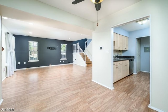 kitchen with light wood-style floors, baseboards, dark countertops, and dishwasher