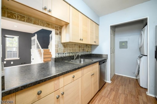 kitchen featuring a sink, stacked washer / drying machine, stainless steel dishwasher, dark countertops, and backsplash