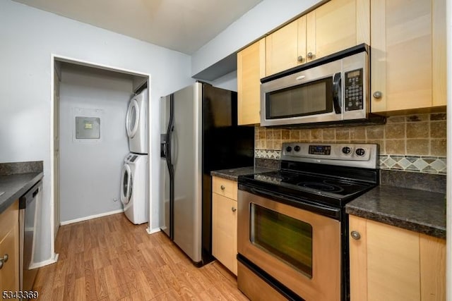 kitchen featuring dark countertops, stacked washer / dryer, tasteful backsplash, and appliances with stainless steel finishes