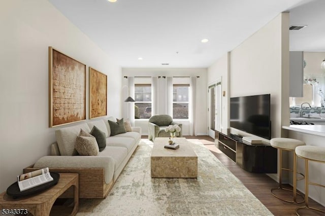 living room with recessed lighting, visible vents, and wood finished floors