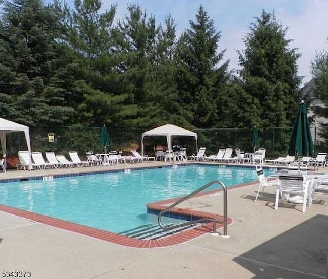 community pool featuring a gazebo, a patio, and fence