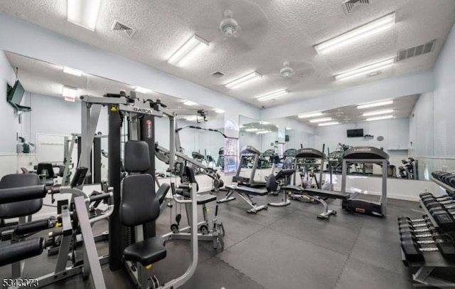 exercise room featuring visible vents, a textured ceiling, and ceiling fan