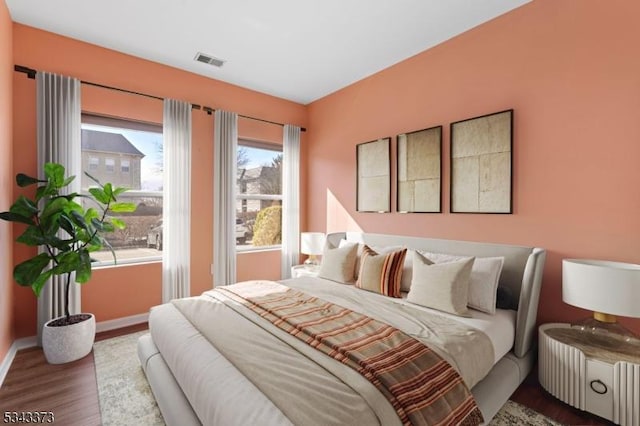 bedroom with wood finished floors, visible vents, and baseboards