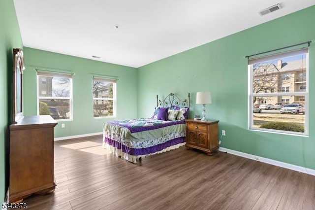 bedroom featuring visible vents, baseboards, and wood finished floors