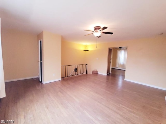 spare room featuring a ceiling fan, wood finished floors, baseboards, and baseboard heating