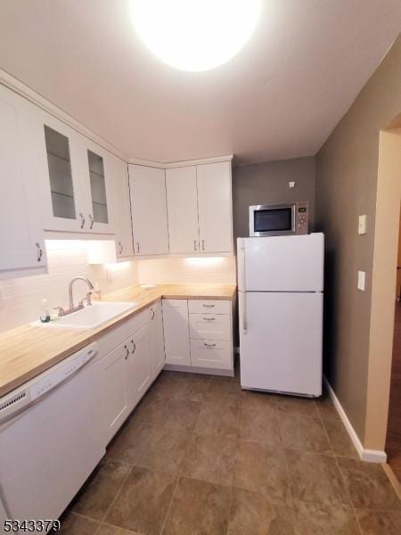 kitchen featuring glass insert cabinets, light countertops, white appliances, white cabinetry, and a sink