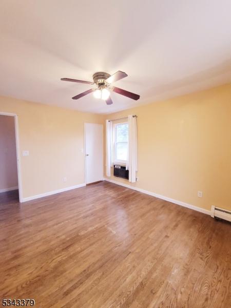 spare room featuring wood finished floors, baseboards, and ceiling fan