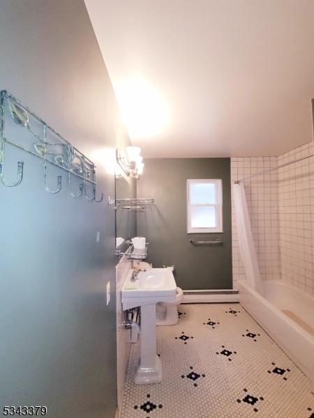 bathroom with a baseboard radiator, shower / bath combination with curtain, and tile patterned flooring