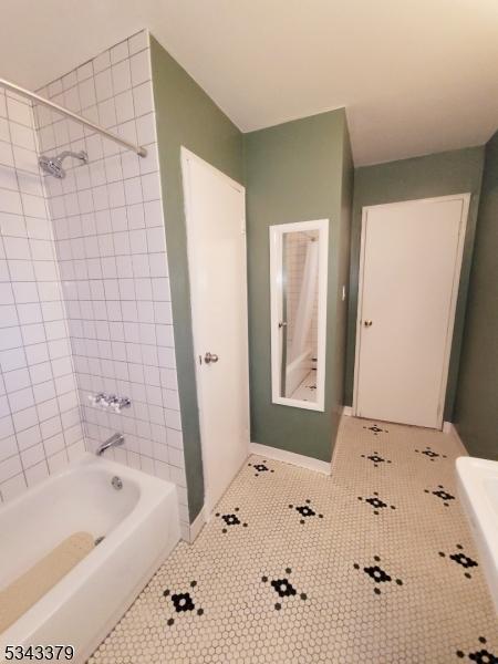 bathroom with tile patterned floors, baseboards, and shower / washtub combination