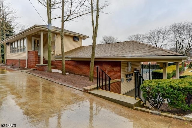 exterior space featuring brick siding and roof with shingles