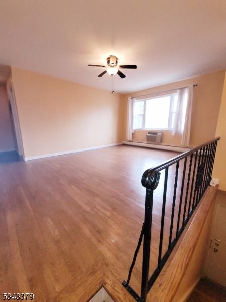 staircase with wood finished floors, baseboards, and ceiling fan