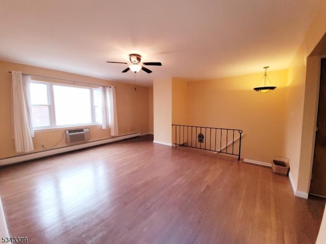 unfurnished room featuring a ceiling fan, wood finished floors, baseboards, an AC wall unit, and baseboard heating