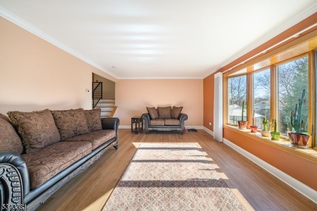 living area with stairway, wood finished floors, baseboards, and ornamental molding