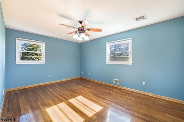 spare room featuring baseboards, wood finished floors, visible vents, and ceiling fan