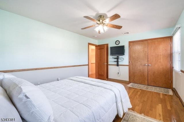 bedroom featuring a ceiling fan, light wood-style flooring, visible vents, and a closet