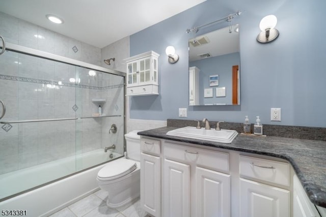 bathroom featuring tile patterned flooring, toilet, vanity, and bath / shower combo with glass door