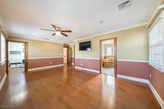 unfurnished room featuring plenty of natural light, wood finished floors, and visible vents