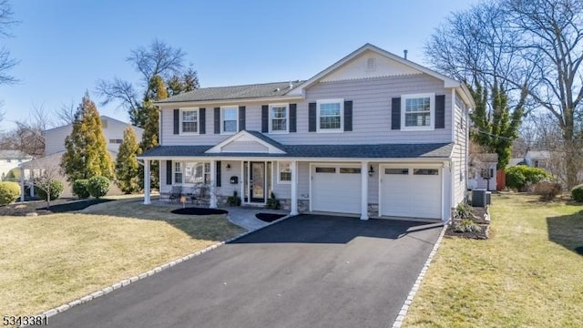 traditional home with a front lawn, a garage, covered porch, and driveway