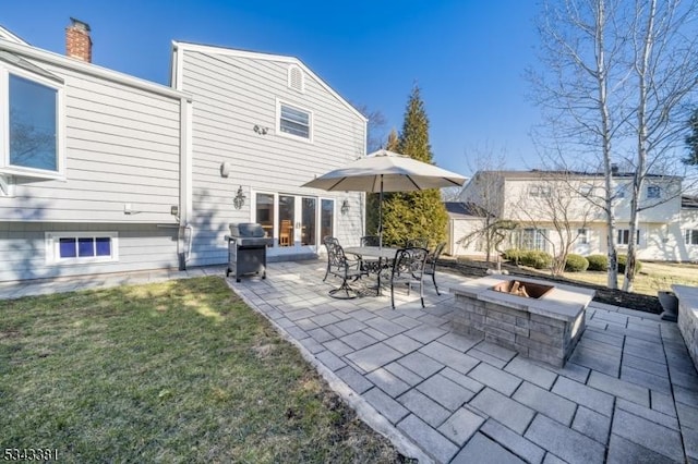 rear view of house with french doors, a fire pit, a lawn, and a patio area