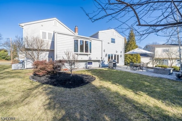 back of house with a patio, a lawn, an outdoor fire pit, and a chimney