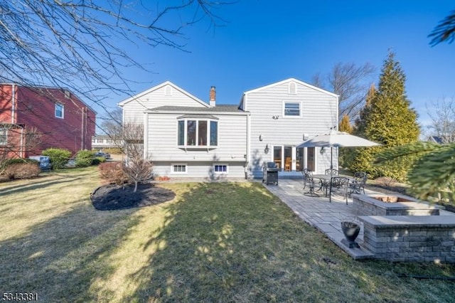 back of house with a patio area, a lawn, and a chimney