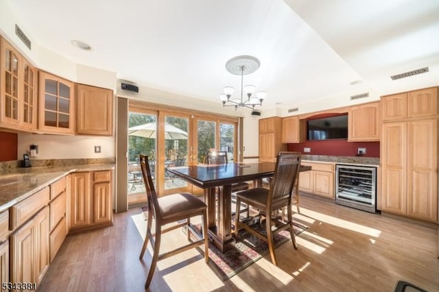 dining space featuring visible vents, light wood-style floors, beverage cooler, and a chandelier